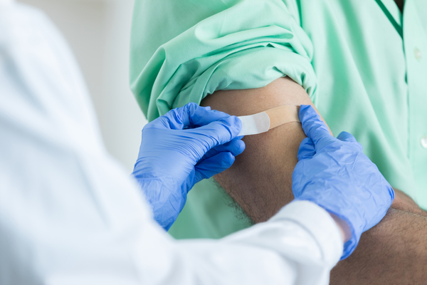 Provider putting a bandaid on a patient after a vaccine