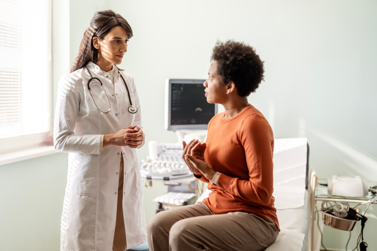 Provider and patient in an exam room. The patient is sitting down talking to the provider