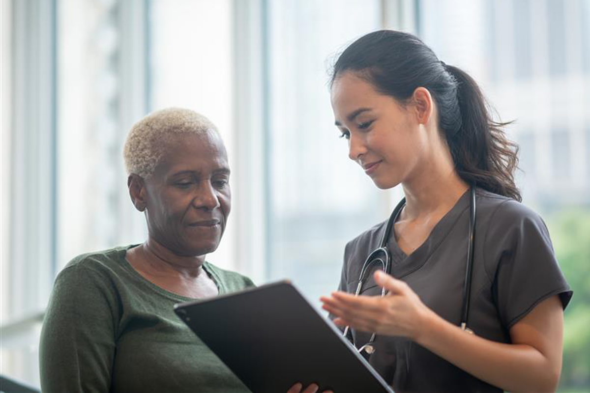 Proveedor hablando con una paciente sobre sus resultados. El proveedor sostiene una tableta