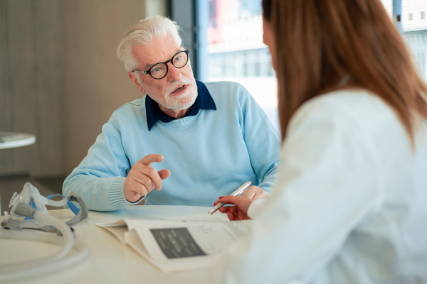 1487491127 Senior patient discussing with doctor at desk in hospital