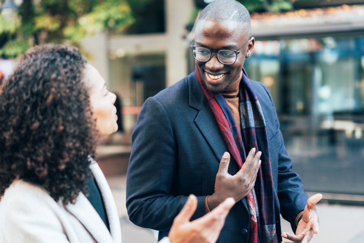 Dos personas caminando juntas por una calle. Se miran el uno al otro con sonrisas