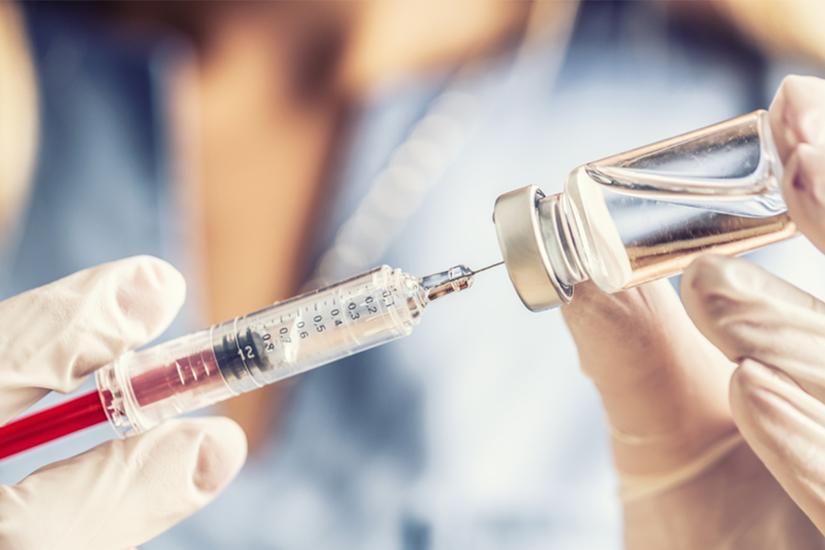 Doctor or nurse in a laboratory preparing a vaccine for a patient.