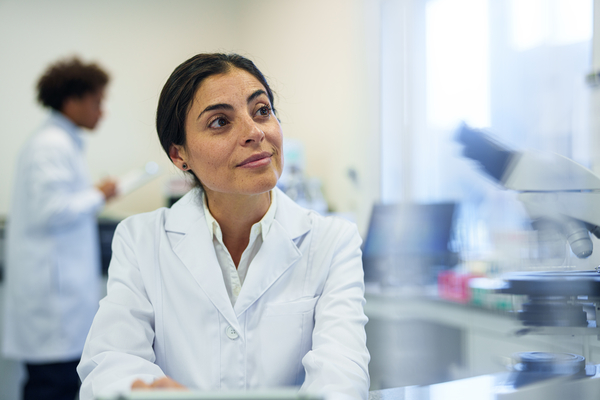 Scientist sitting inside of a lab. She is typing on a computer