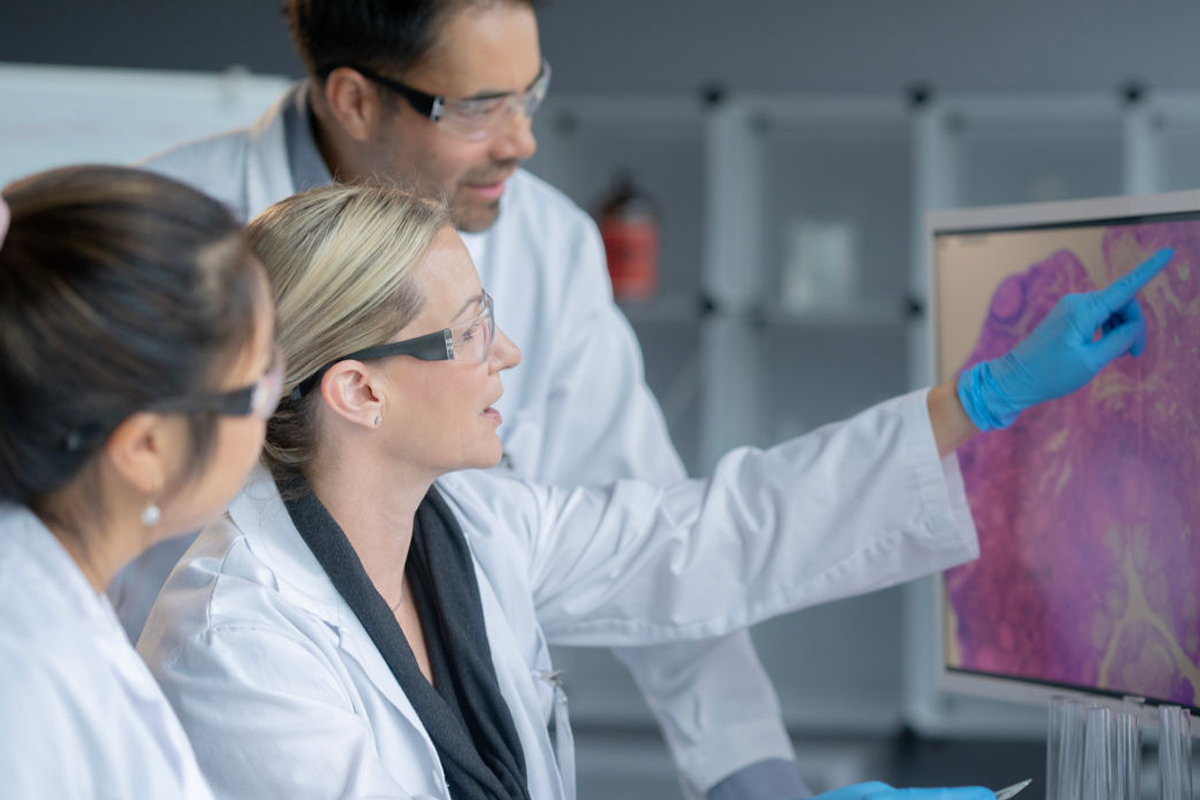 Photo of multiple scientists focusing in on a screen.