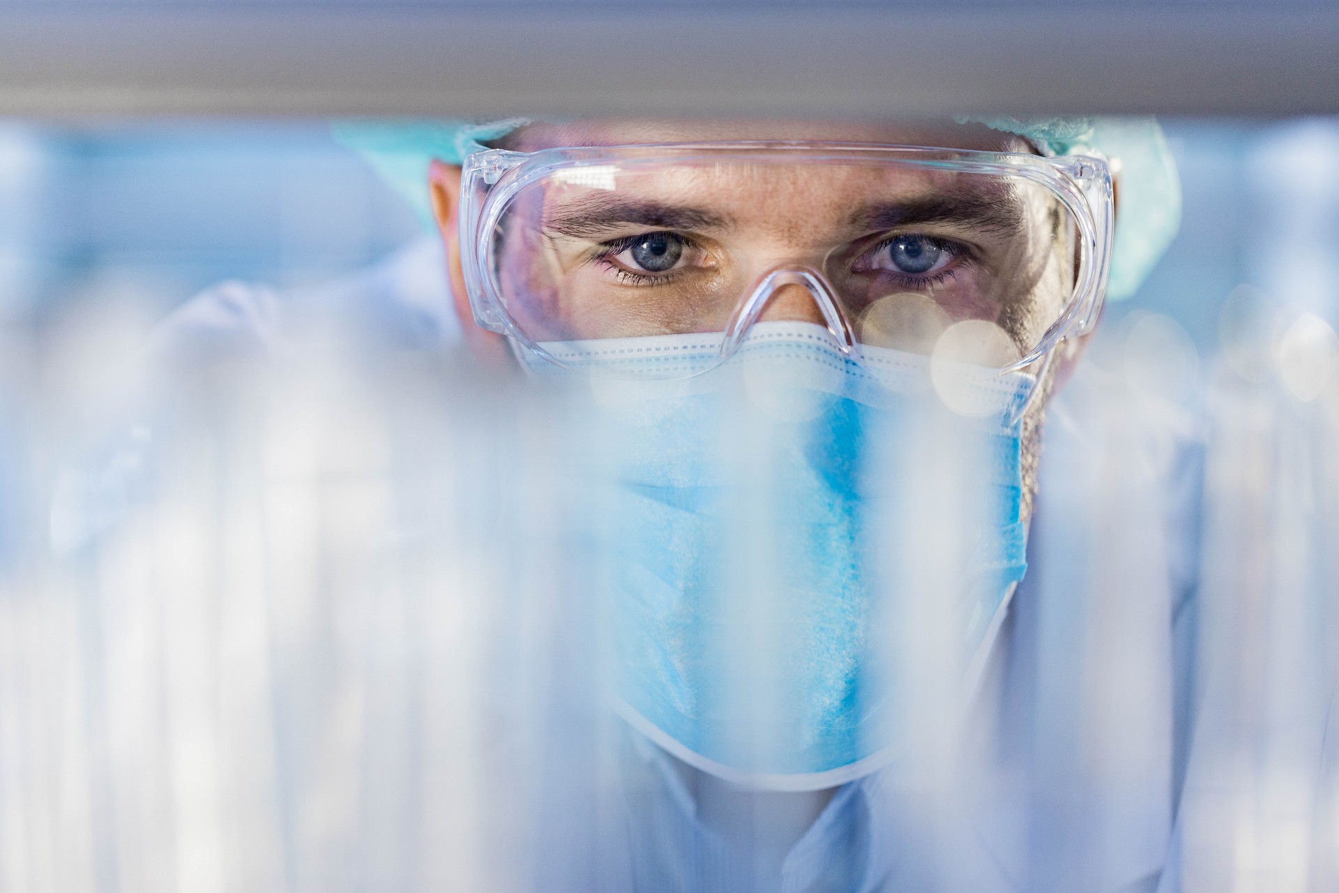Scientist looking into a stack of vails. He is wearing proper protective wear